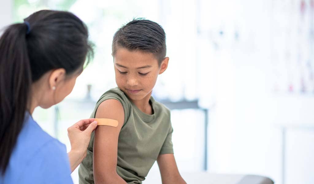 Provider applying a bandaid to a young member's arm in the office.