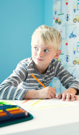 Boy doing homework at desk in children's room