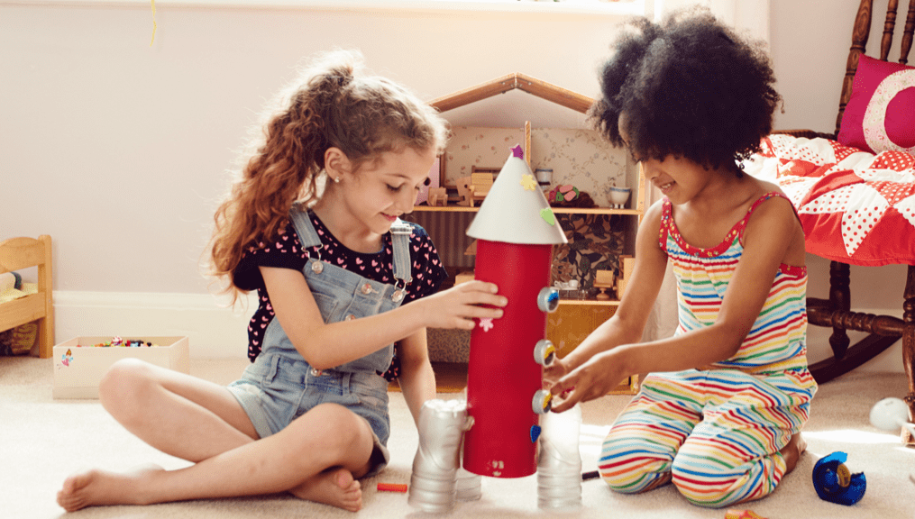 Two children working together to build a toy rocket ship