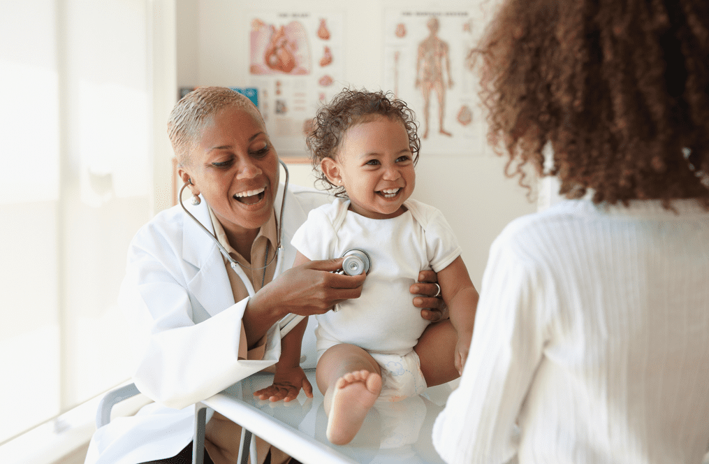 Baby laughing with female doctor and mom