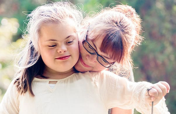 Young girl with Down syndrome hugging her mom