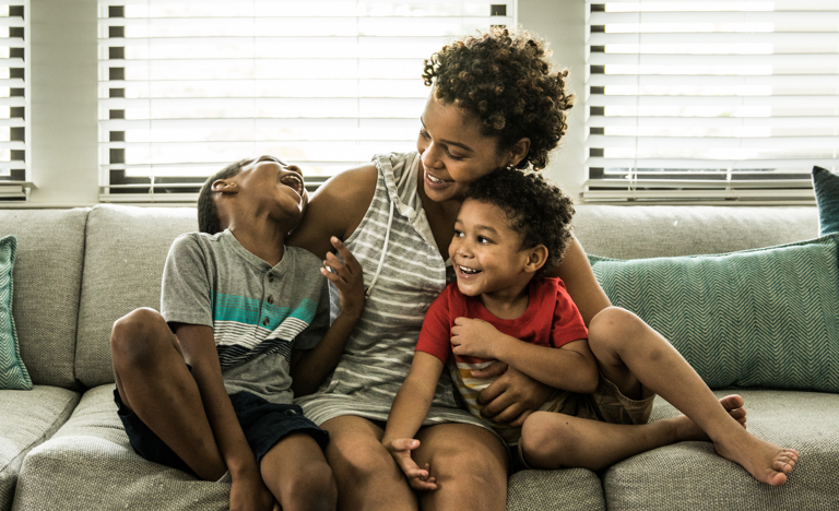 Mother playing with young sons on couch