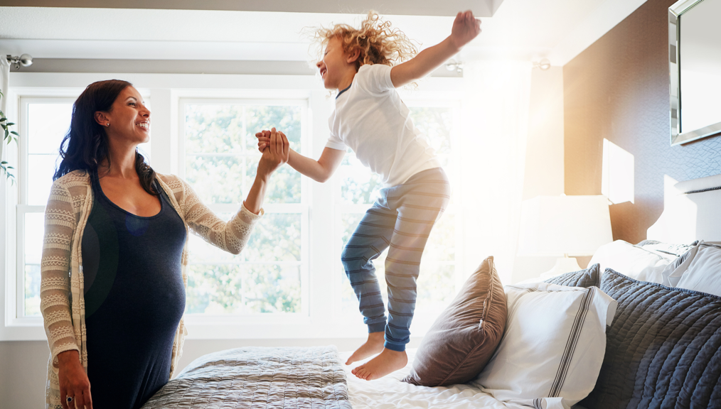 Pregnant woman bonding with her young son at home
