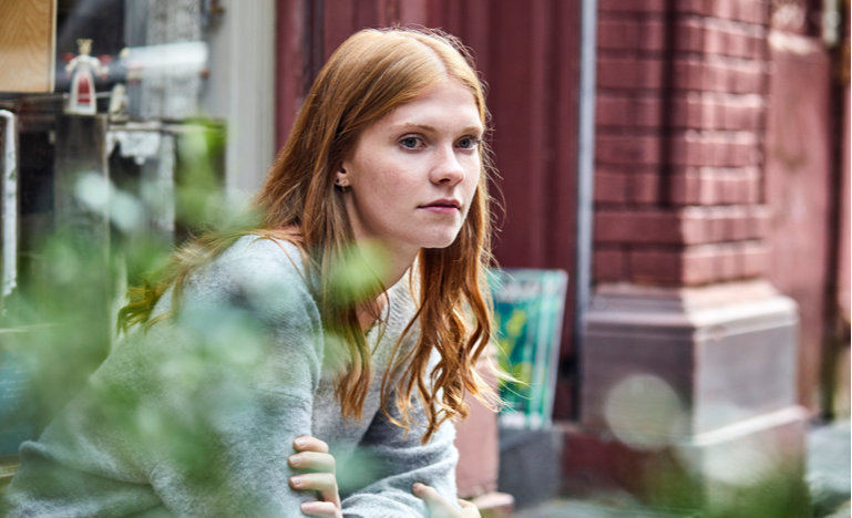 Young woman sitting at house entrance