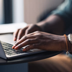 Doctor's hands typing on a laptop keyboard as they search for digital resources online.