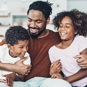 Father sitting hugging his two children.