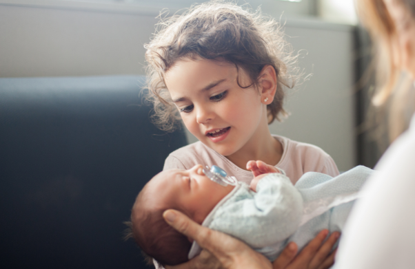 Young girl holding a newborn baby