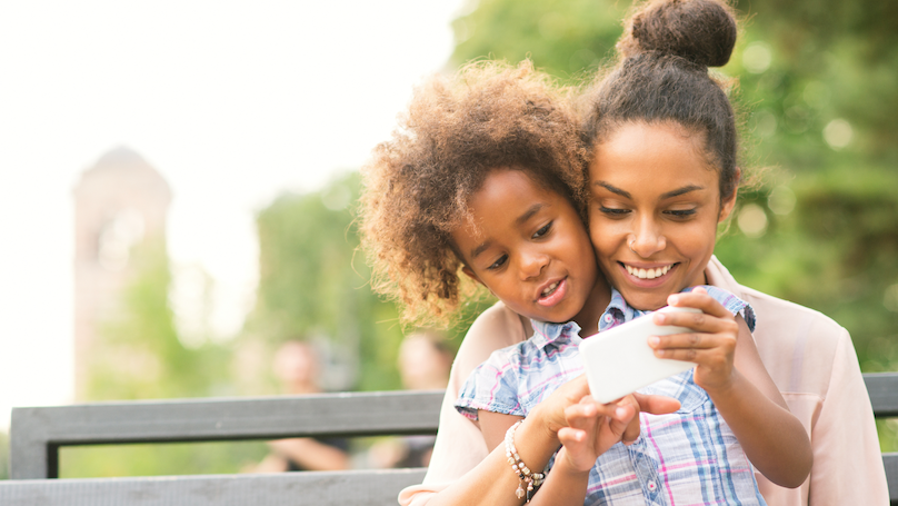 Mother and daughter using smartphone in the park