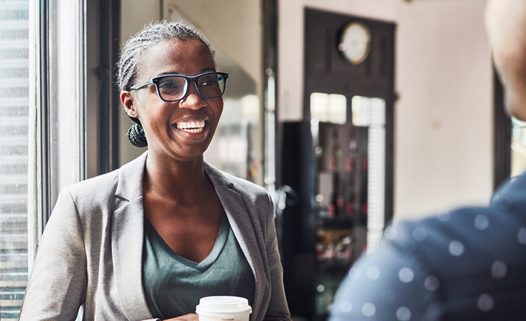 Smiling woman talking with her colleague while having coffee