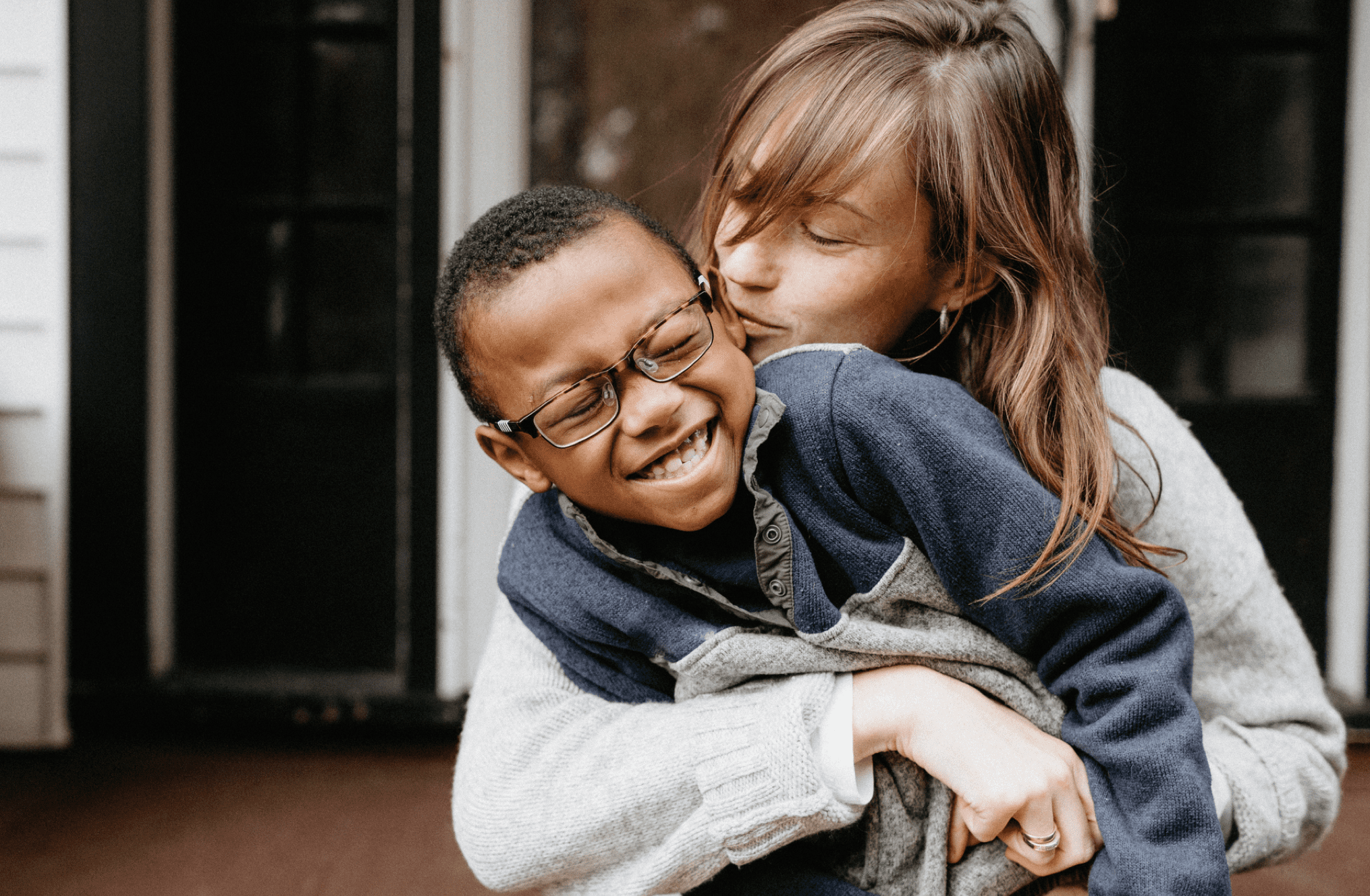 A mother and her son smiling, laughing and cuddling on the front porch