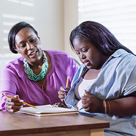 Teenager with Down syndrome working on a document with her mother