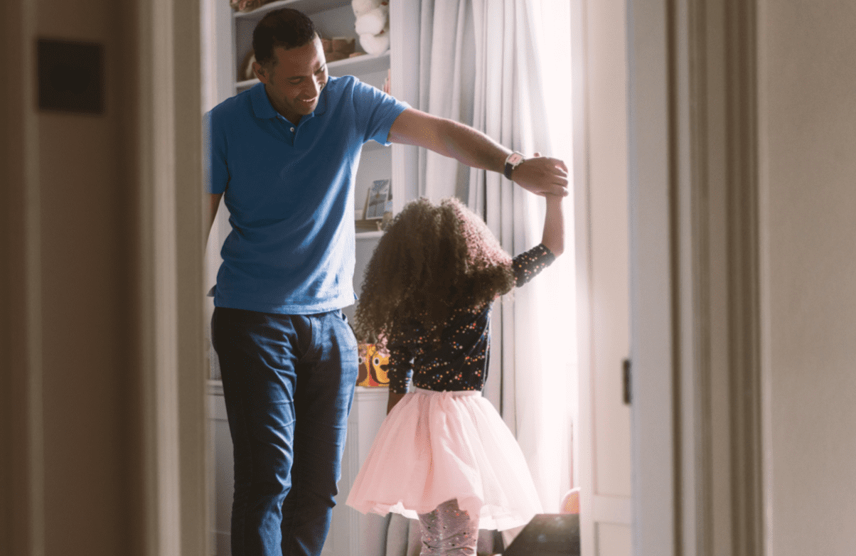 Father dancing with daughter in bedroom