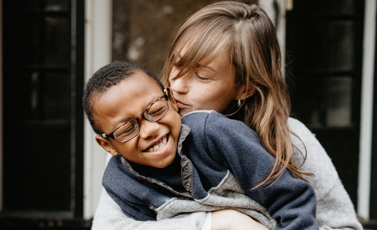 A mother and her son smiling, laughing and cuddling on the front porch